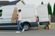 Man Carrying Boxes Beside a Van